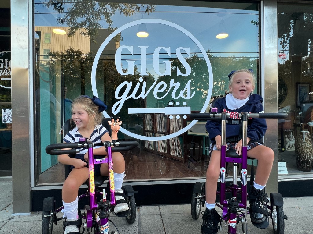 Two friends smiling outside the GIGS givers window