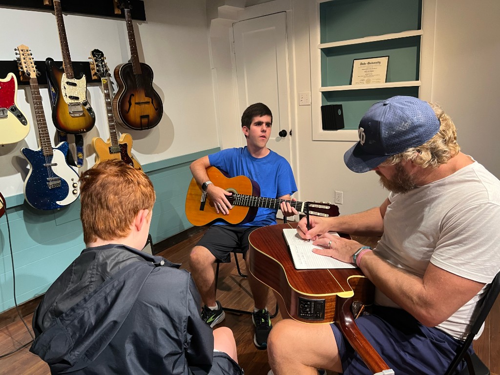 Student standing with acoustic guitar